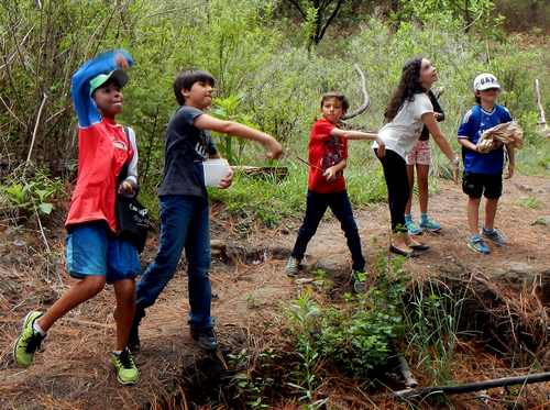 Kids from “Help the Children, Please!” throw milkweed seed bombs